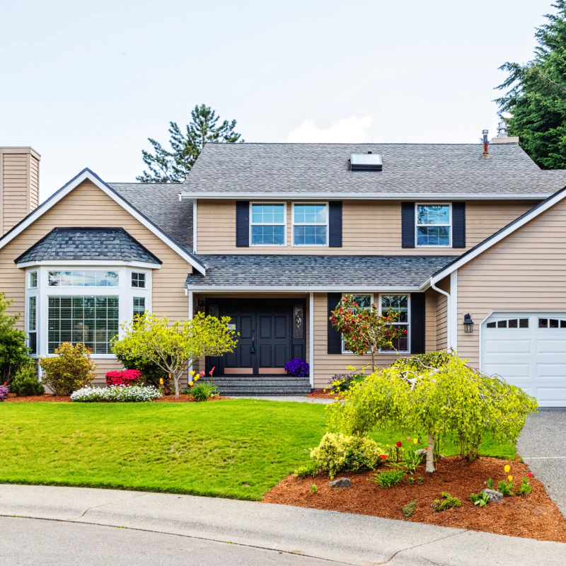 house with light tan siding and dark shutters